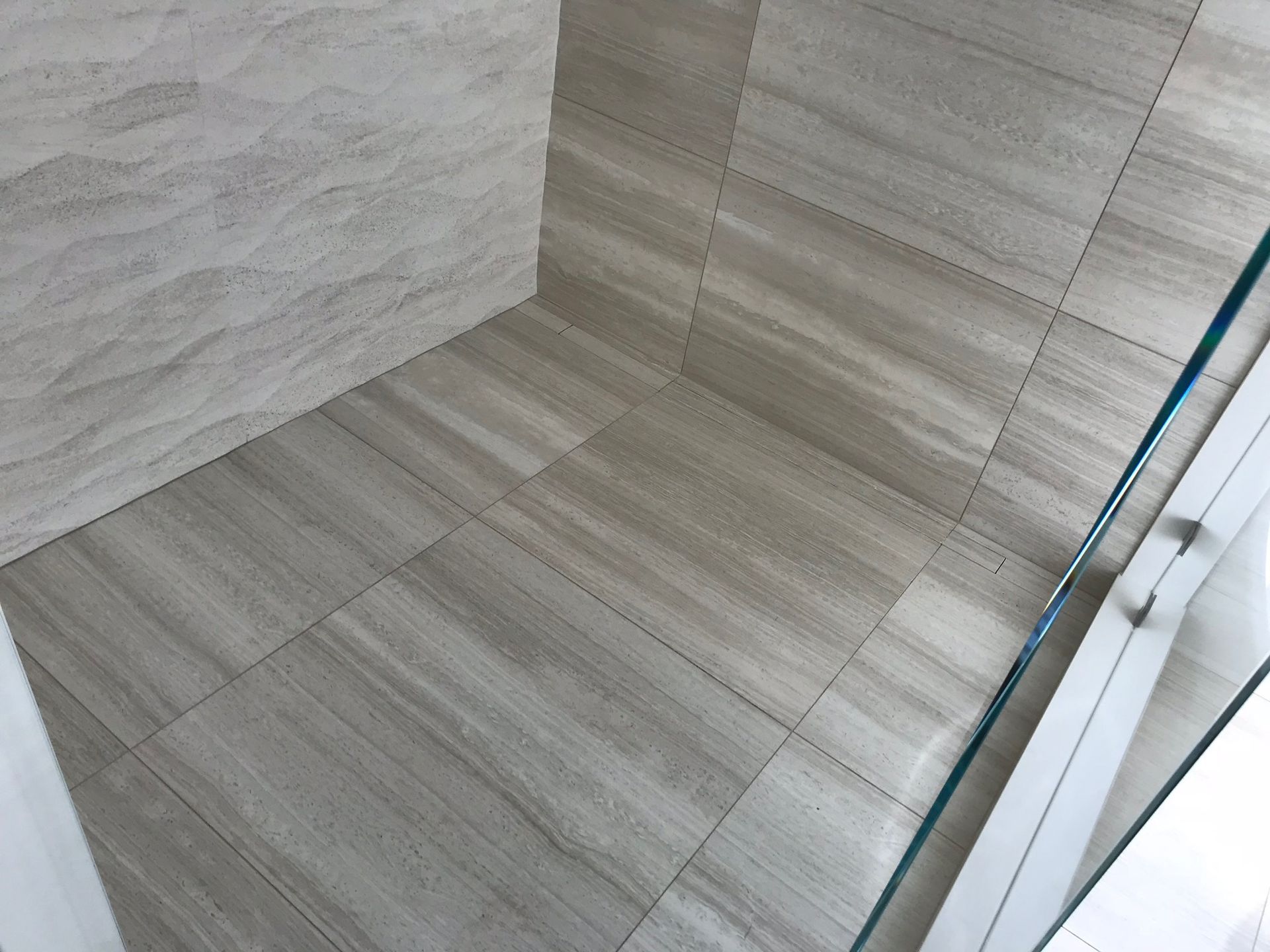 A bathroom with a tiled floor and a glass shower door.