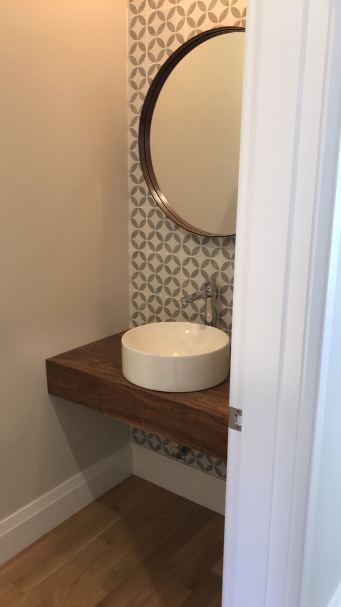 A bathroom with a sink , mirror and wooden counter top.