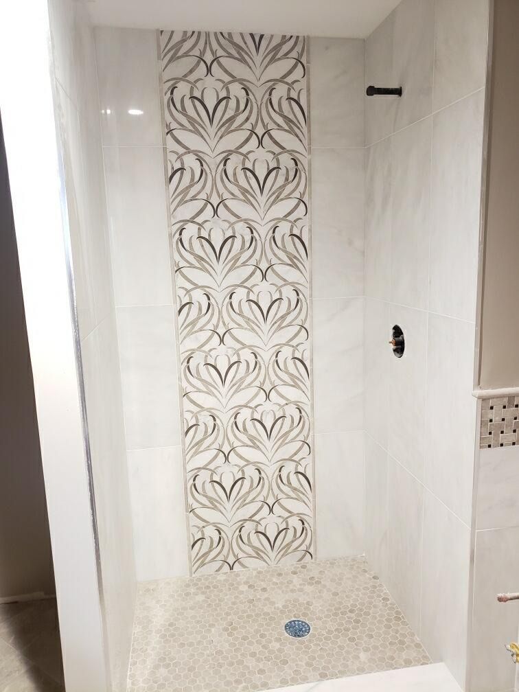 A white shower with a black and white pattern on the wall.