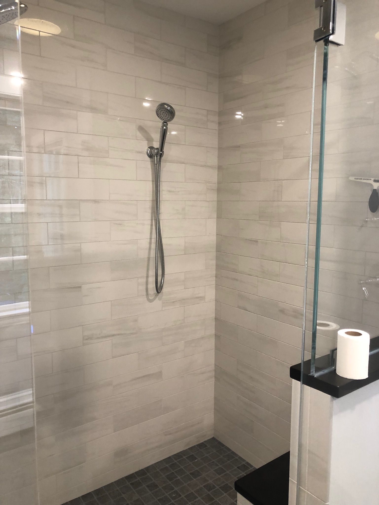 A bathroom with a walk in shower and a toilet paper roll on the counter.