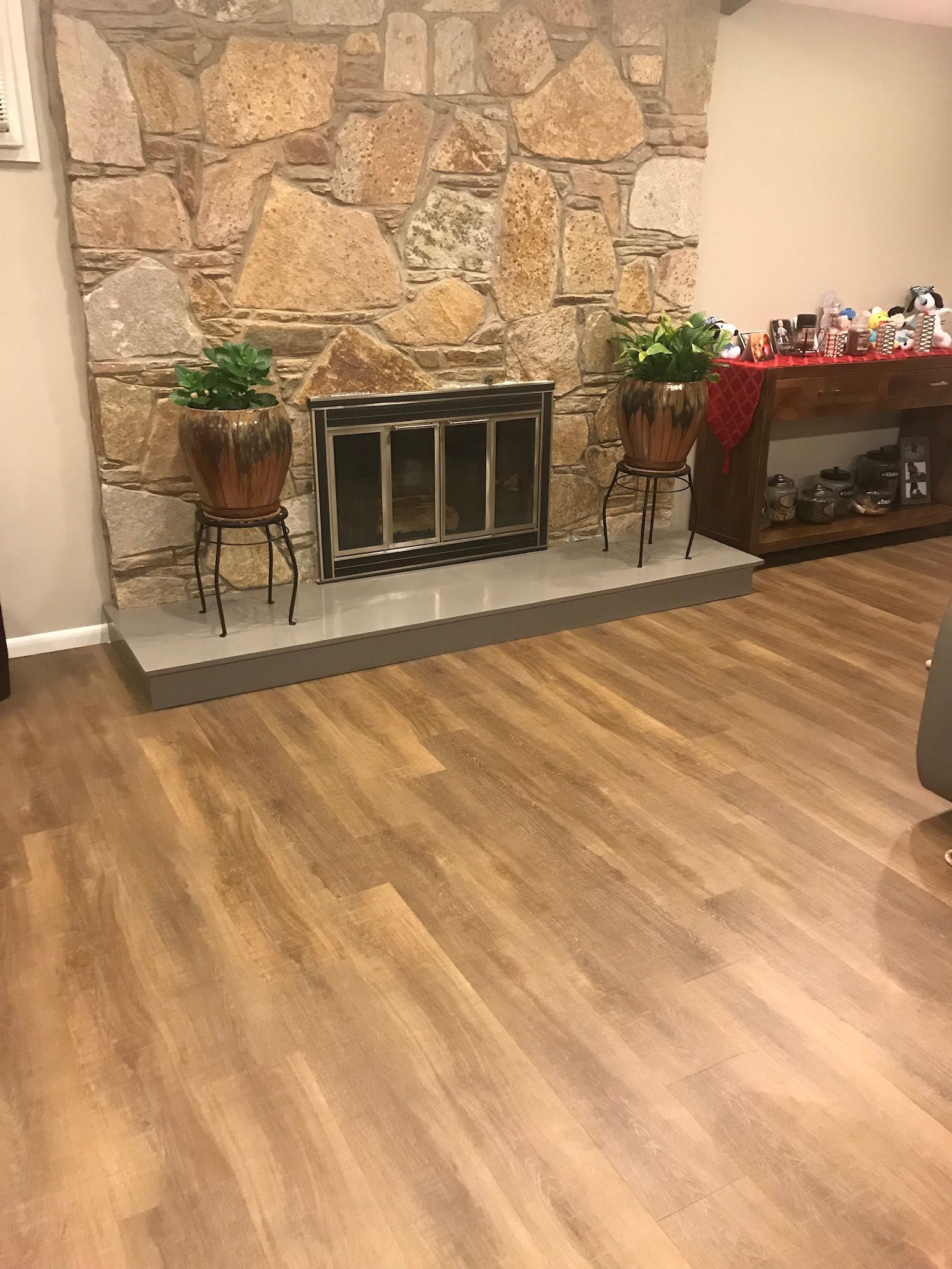 A living room with hardwood floors and a stone fireplace.