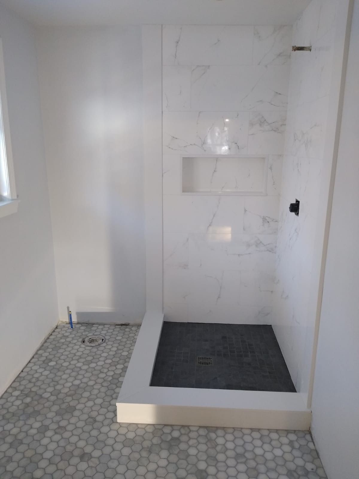 A bathroom with a walk in shower and a window.