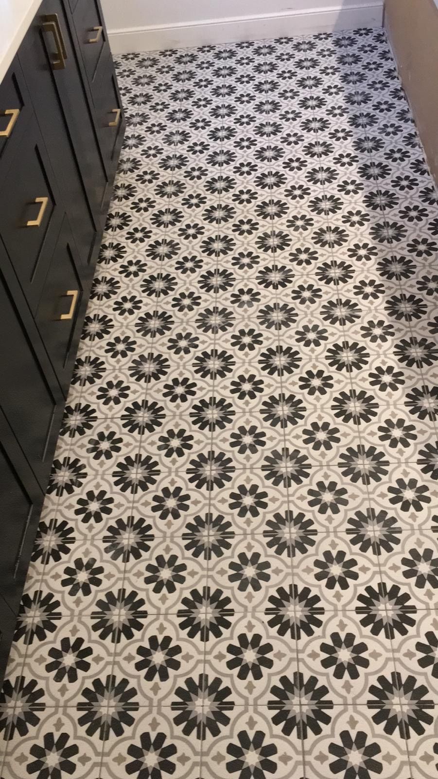 A black and white tile floor with a floral pattern in a bathroom.