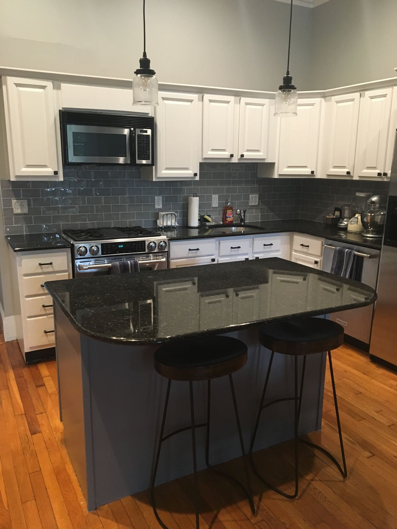 A kitchen with white cabinets and black counter tops