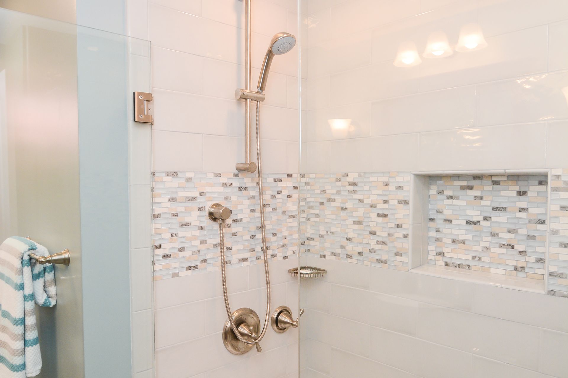 A bathroom with a walk in shower with a glass door and a shower head.
