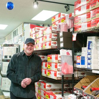 A man is standing in a store surrounded by boxes and shelves