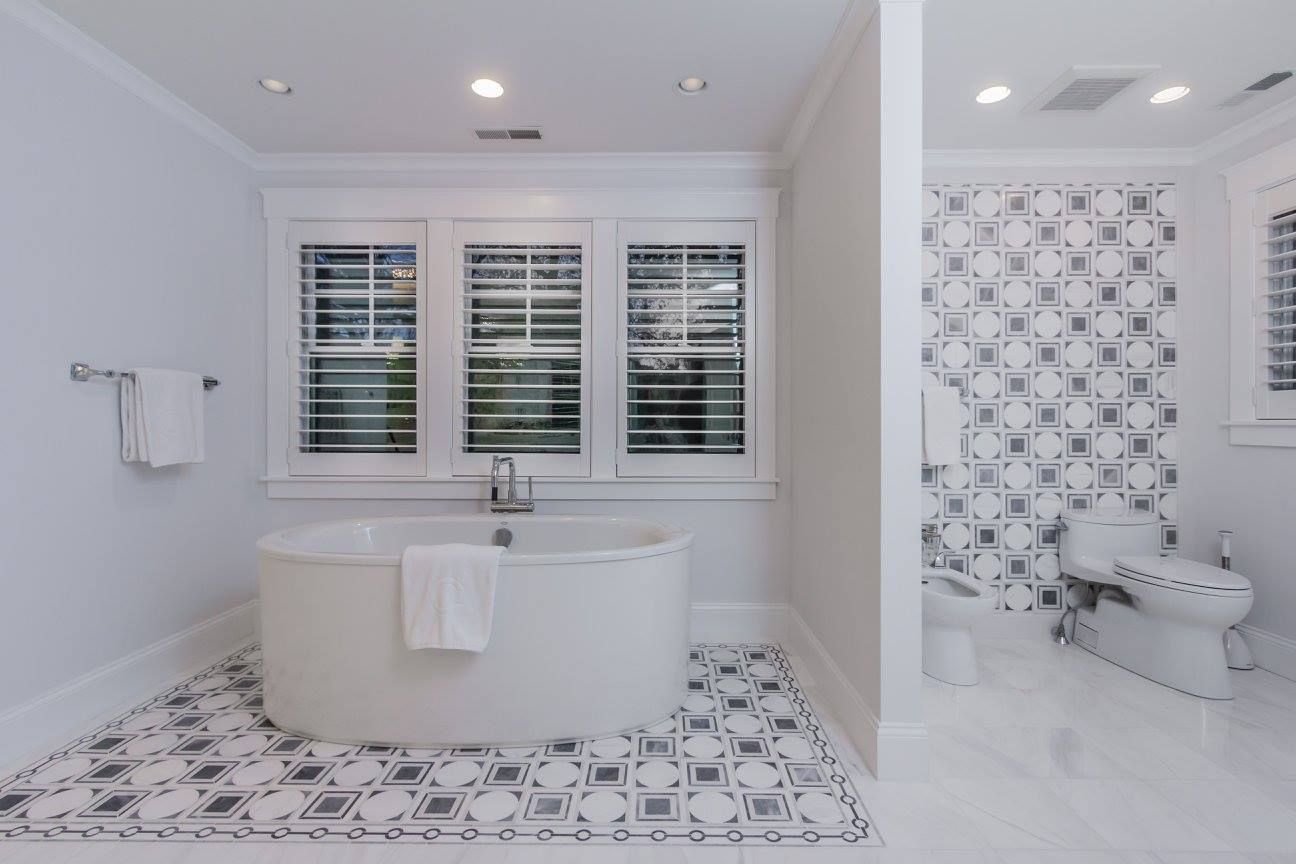 A bathroom with a tub , toilet , sink and window.