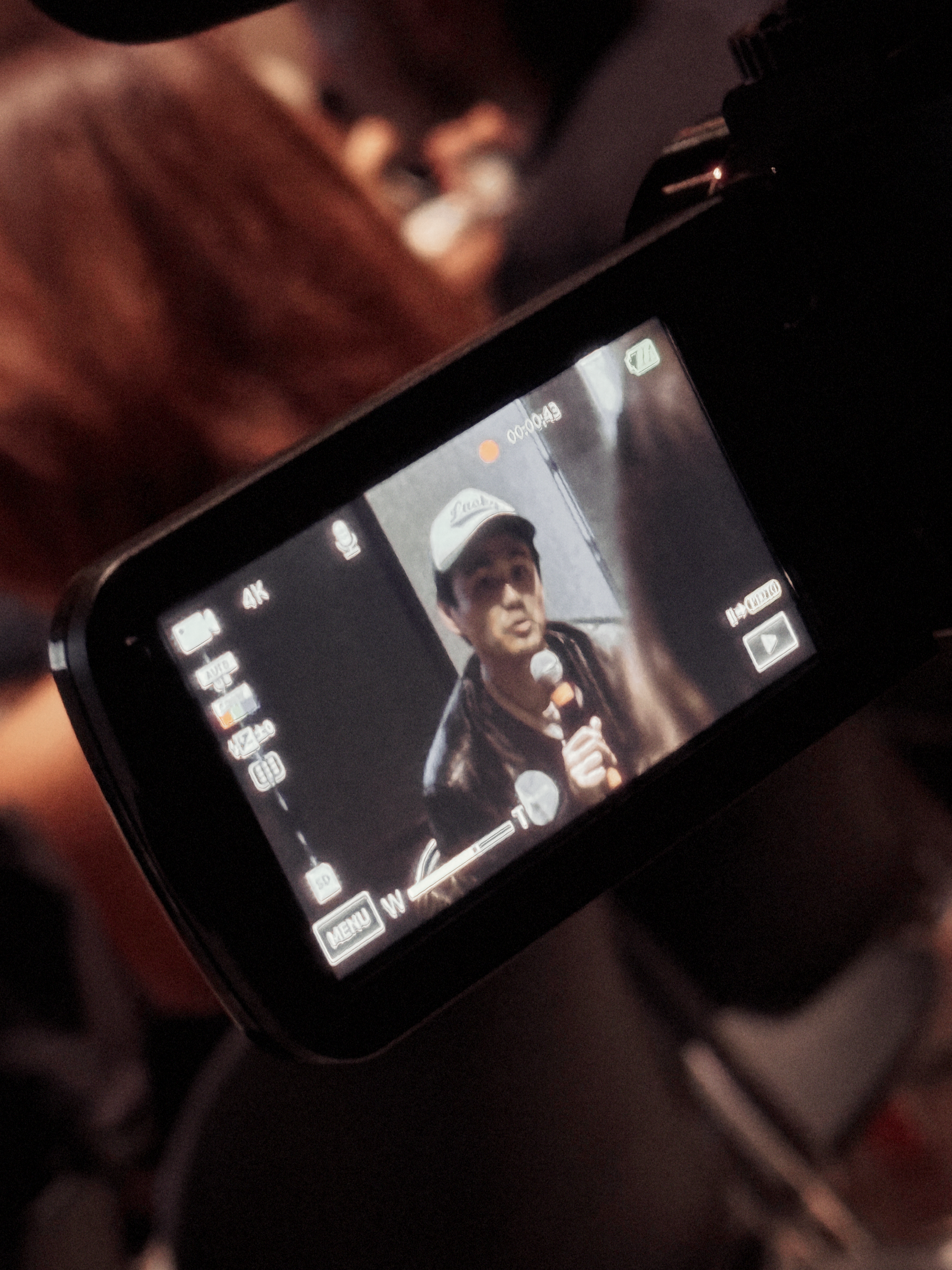 A video camera is recording a man speaking into a microphone