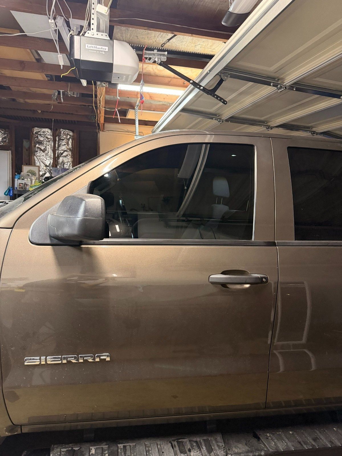 A side view of a tan GMC Sierra pickup truck parked inside a garage.