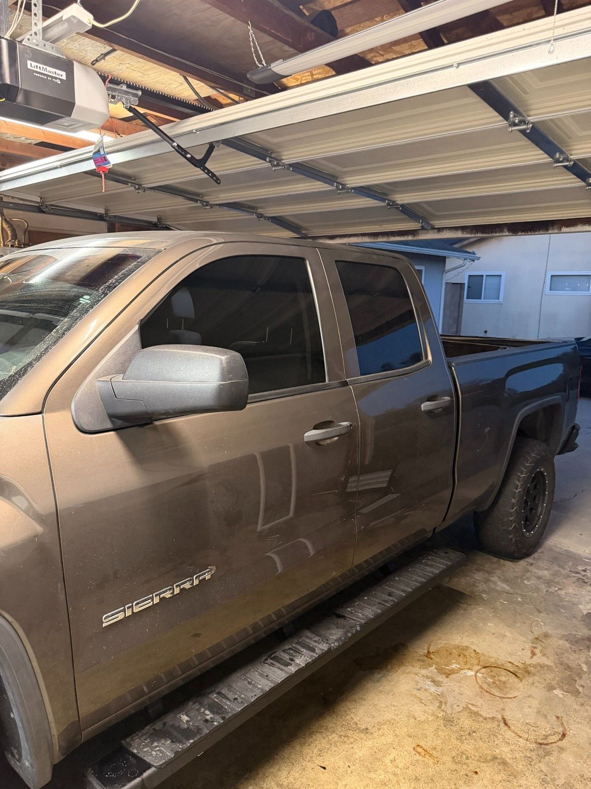A tan crew cab Chevrolet Silverado truck parked inside a garage.