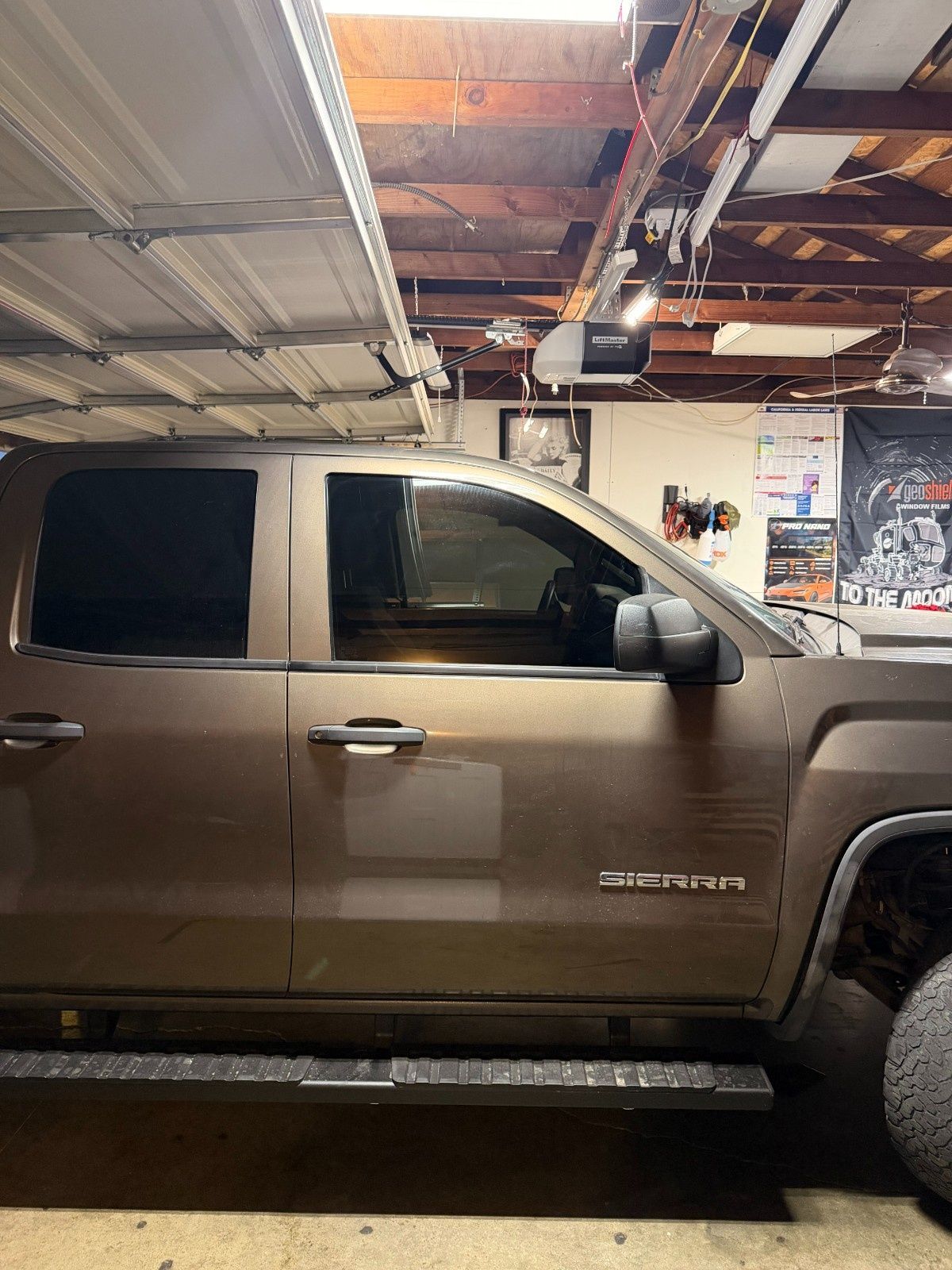 A brown GMC Sierra pickup truck parked inside a cluttered residential garage.