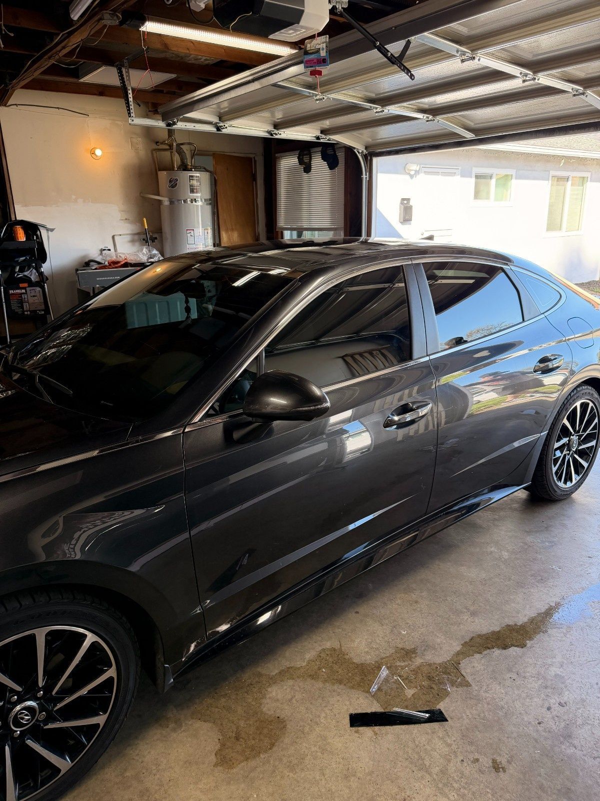 A dark gray sedan parked inside a residential garage, viewed from the side.