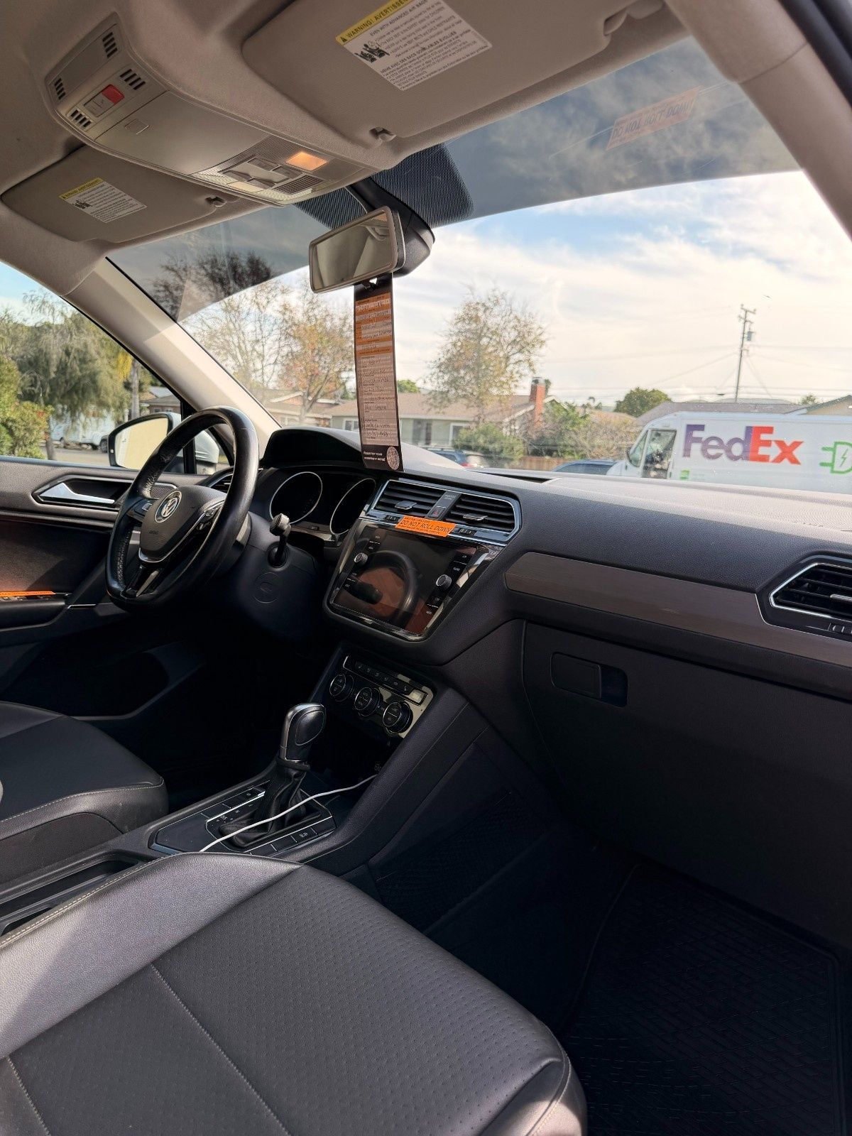 The interior view from the driver's seat of a car, showing the dashboard, steering wheel, and a FedEx truck ahead.