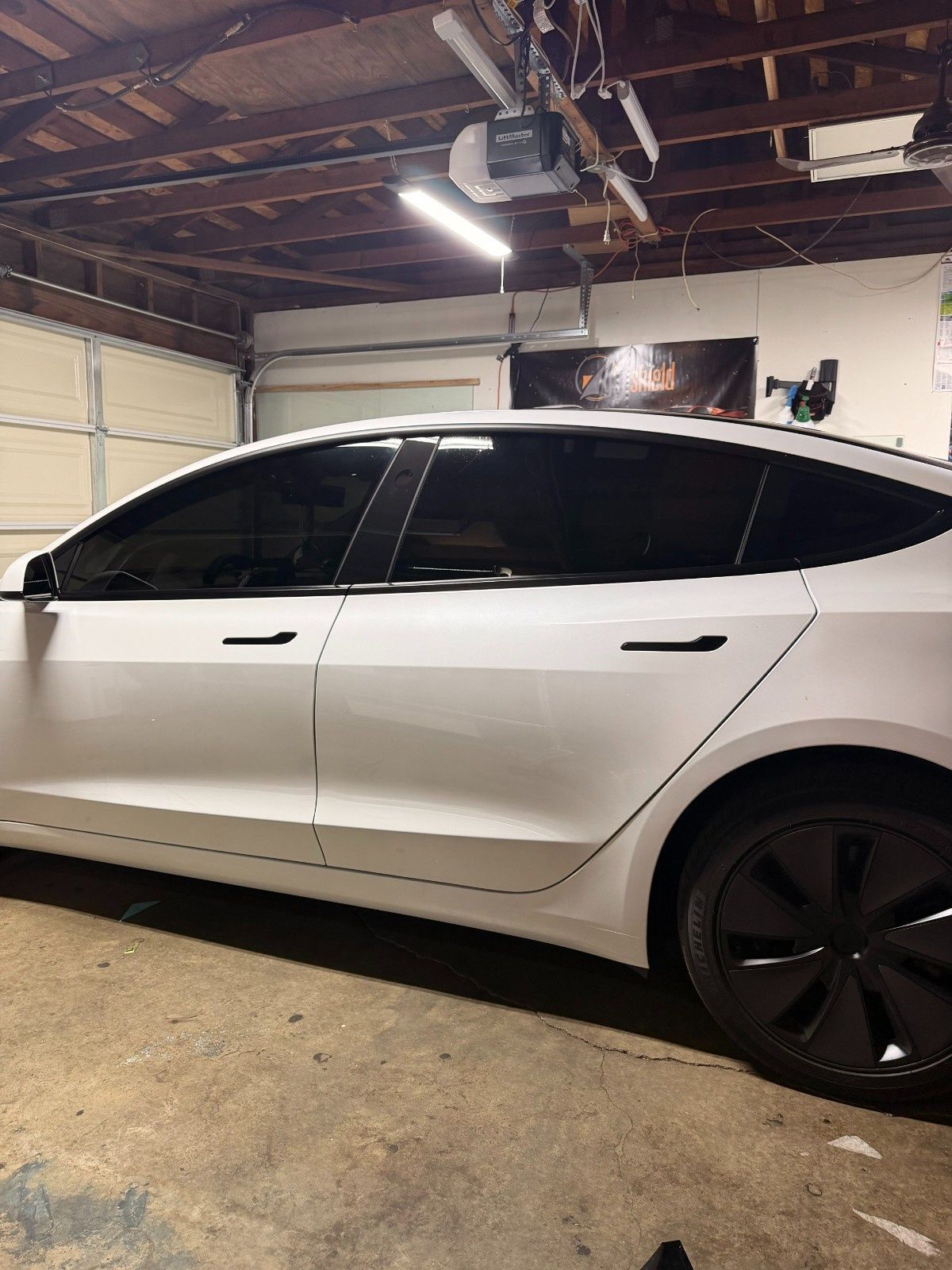 White Tesla with dark tinted windows parked inside a garage.