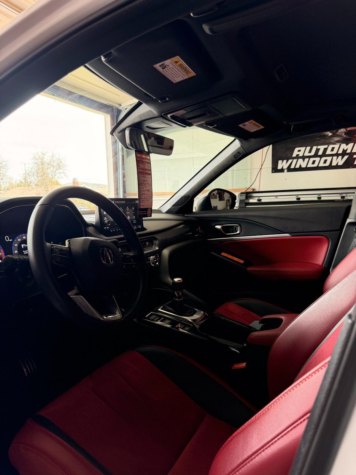 Car interior featuring a black steering wheel, a dark dashboard, and striking red leather upholstery on the front seats.