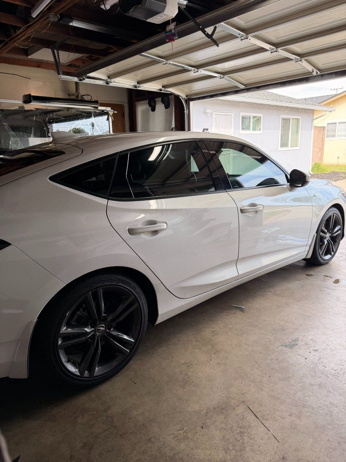 A white sedan with dark rims parked in a garage.