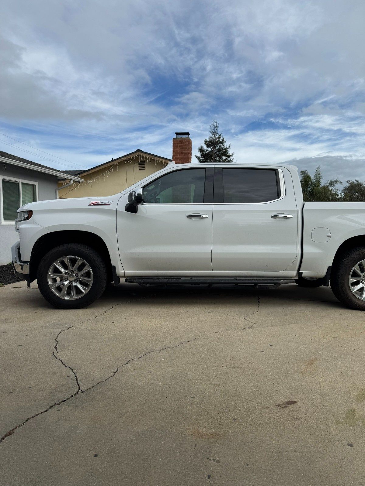 A white Chevrolet Silverado pickup truck parked on a residential driveway on a cloudy day.