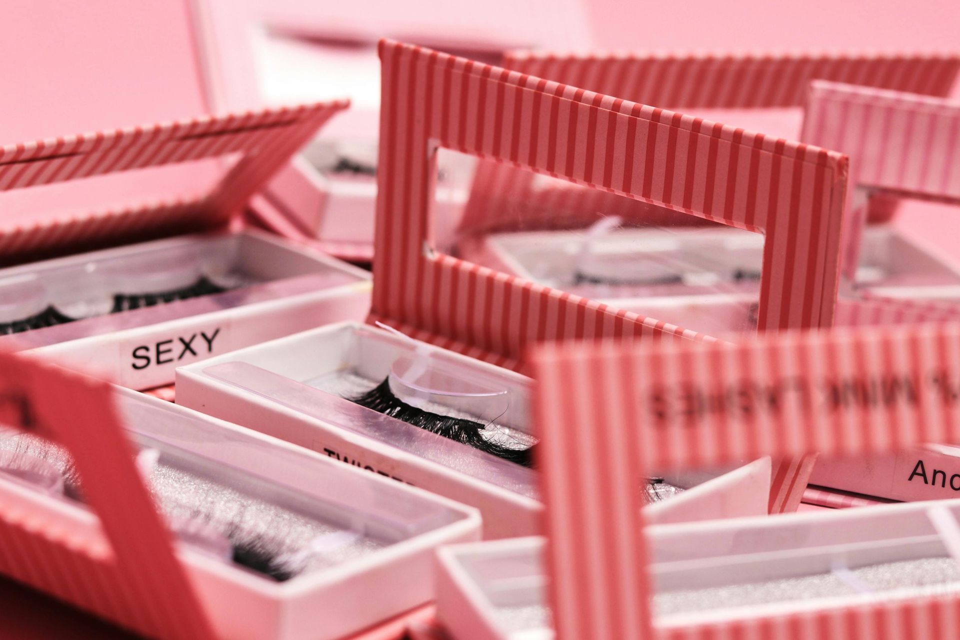 Close-up of pink and white eyelash boxes, some labeled 