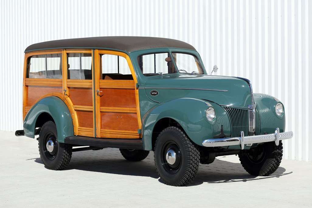 Vintage green and wood-paneled station wagon in a studio setting, side view.