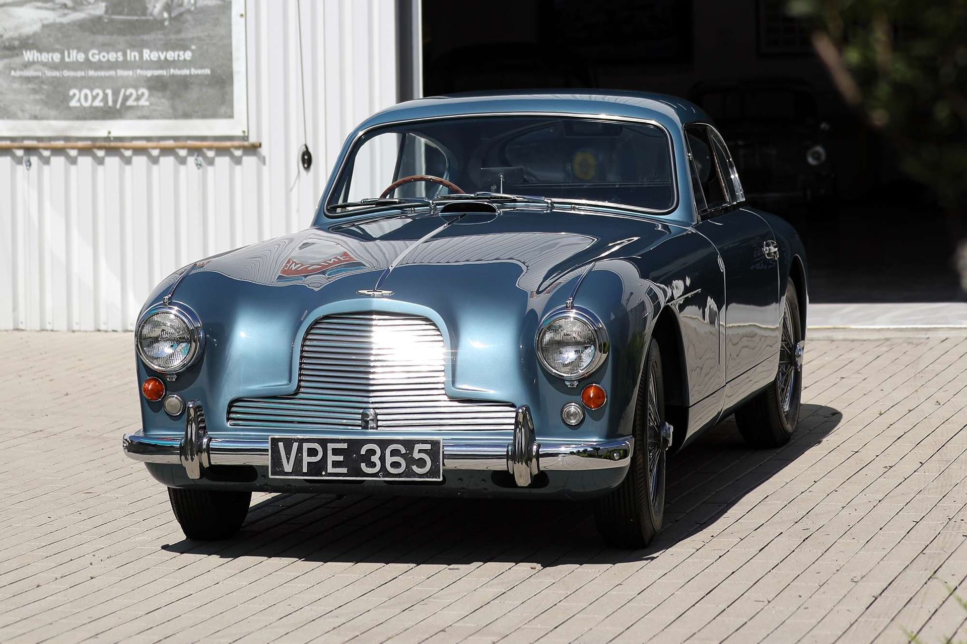 Blue vintage car parked outside a garage, front view