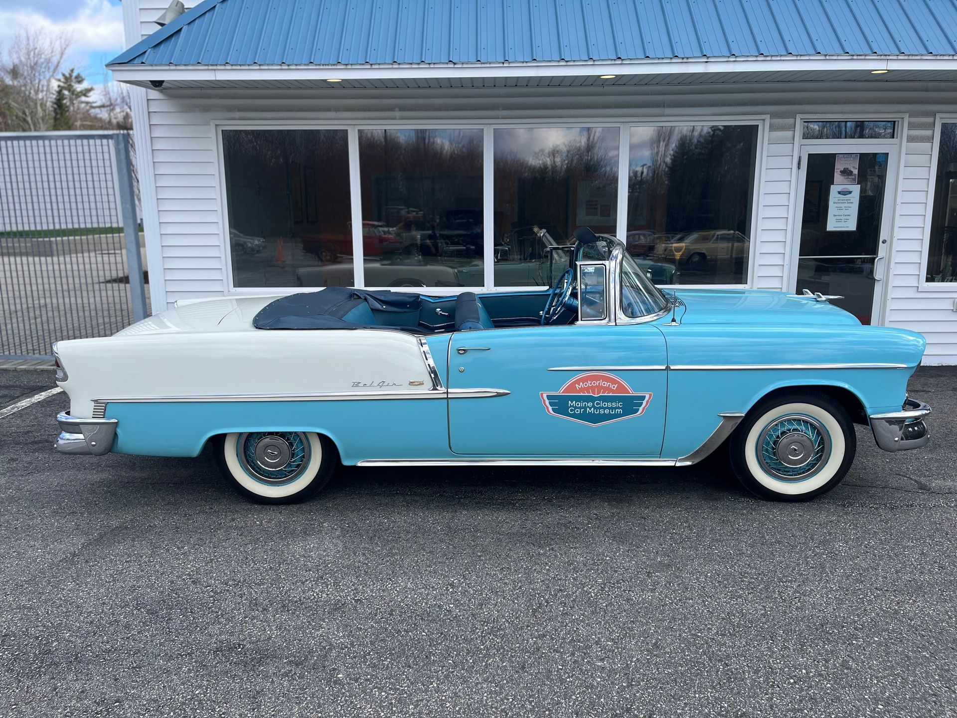 Classic light blue and white vintage convertible parked outside a building