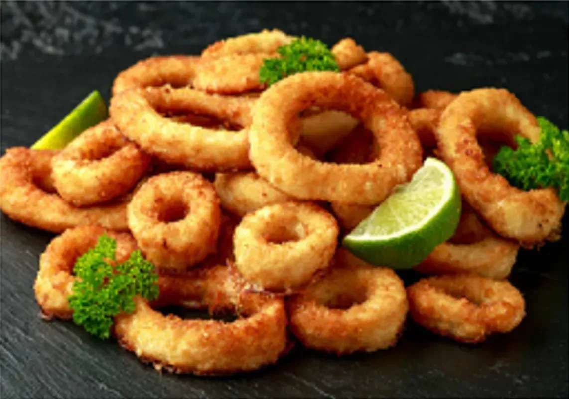 Fried Calamari Rings on a Dark Slate, Garnished With Lime and Parsley — Pt Cartwright Seafoods in Warana, QLD