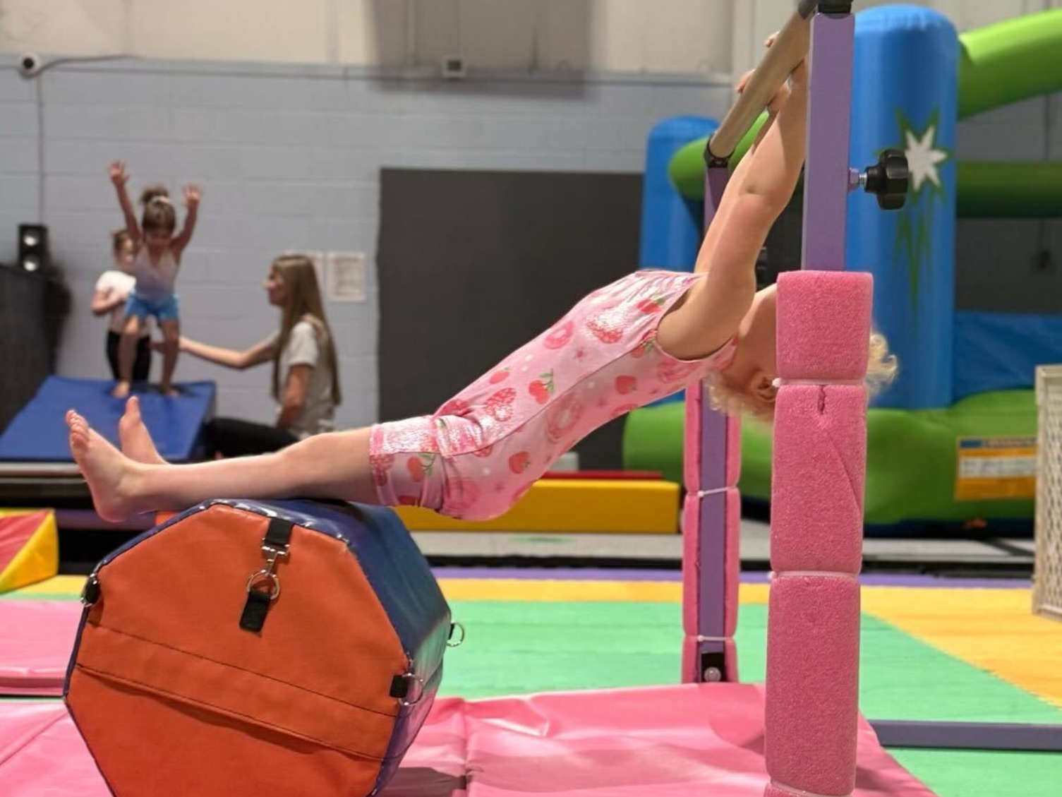 A group of young girls are standing on a balance beam.