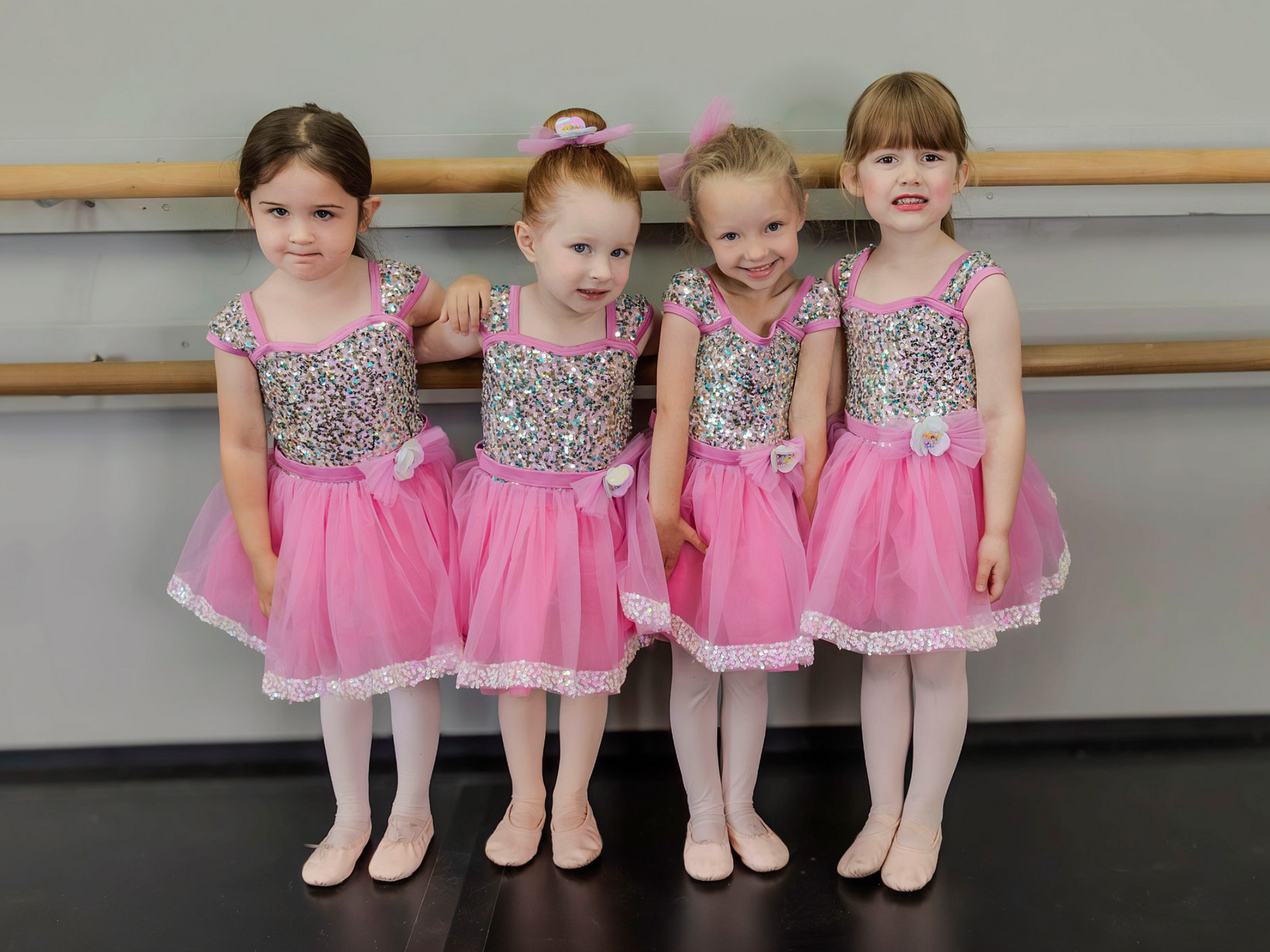 Three young women are practicing ballet in a dance studio.