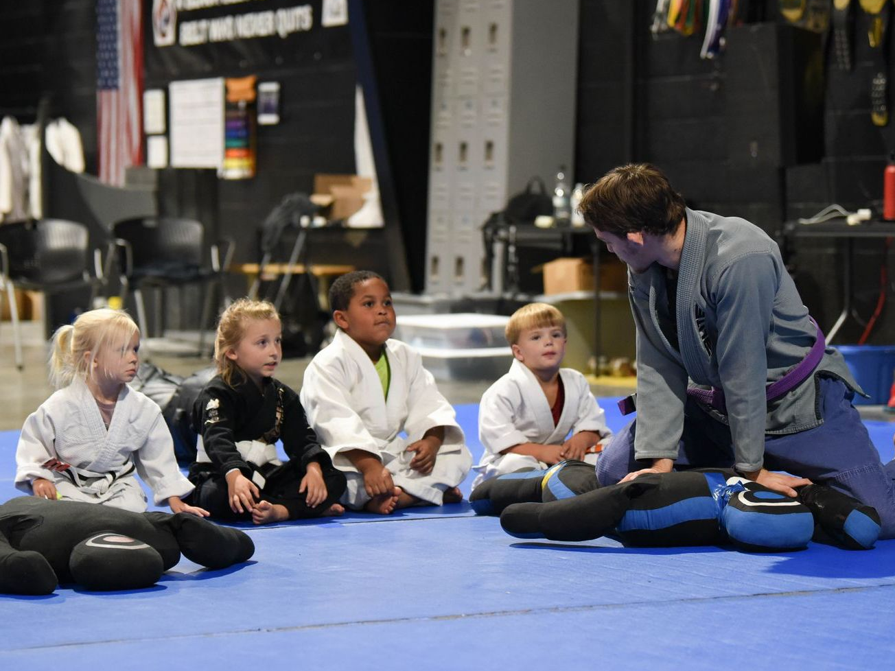 A little girl in a karate uniform is standing on a mat