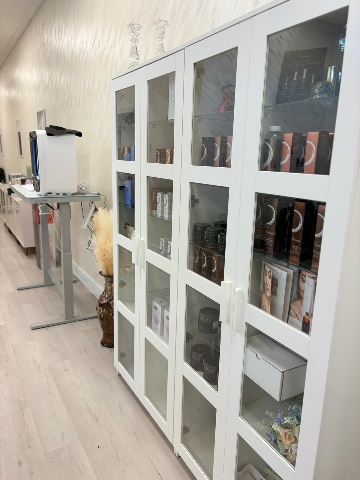 White hallway with glass-front cabinets and a projector on a stand, viewed from an angle