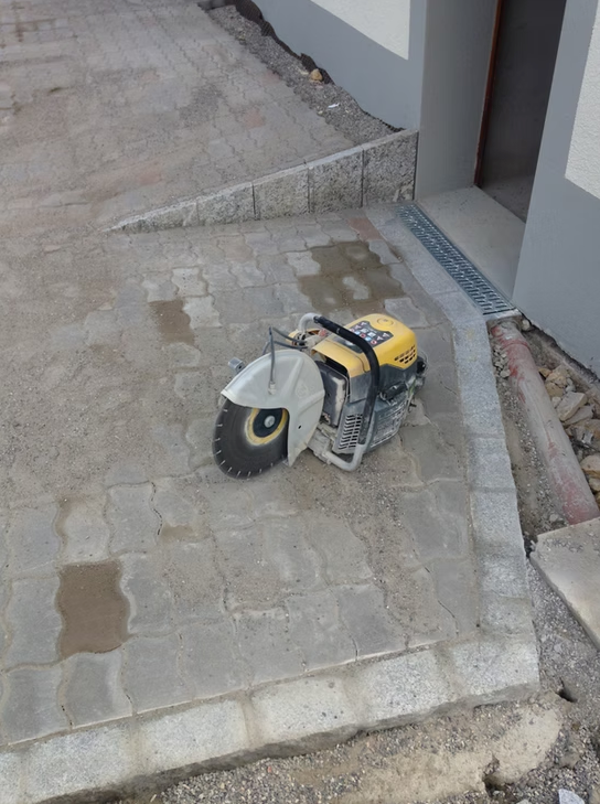 Scie à démolir jaune sur un trottoir en béton à côté de l'entrée d'un bâtiment