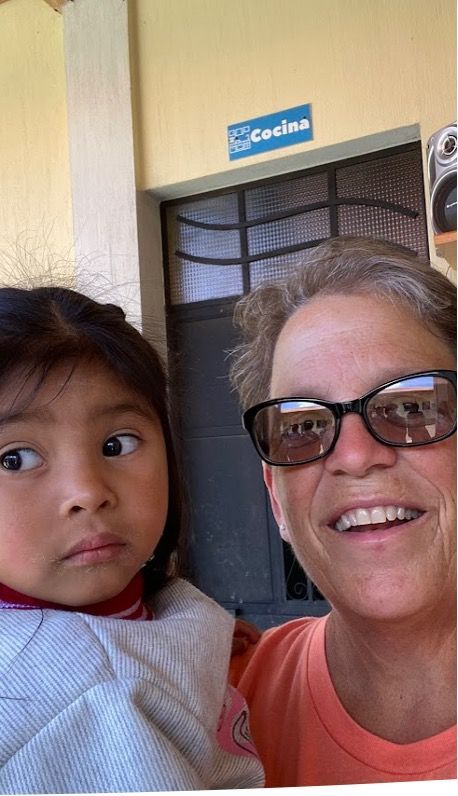 Contact Daily Grace A woman wearing sunglasses is holding a little girl in her arms.