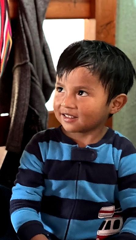 An impoverished Guatemalan boy wearing a blue and black striped shirt with the number 10 on it