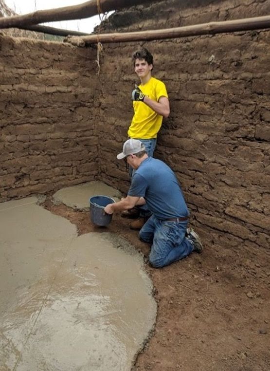 DONATE NOW Two men are working on a concrete floor in a room
