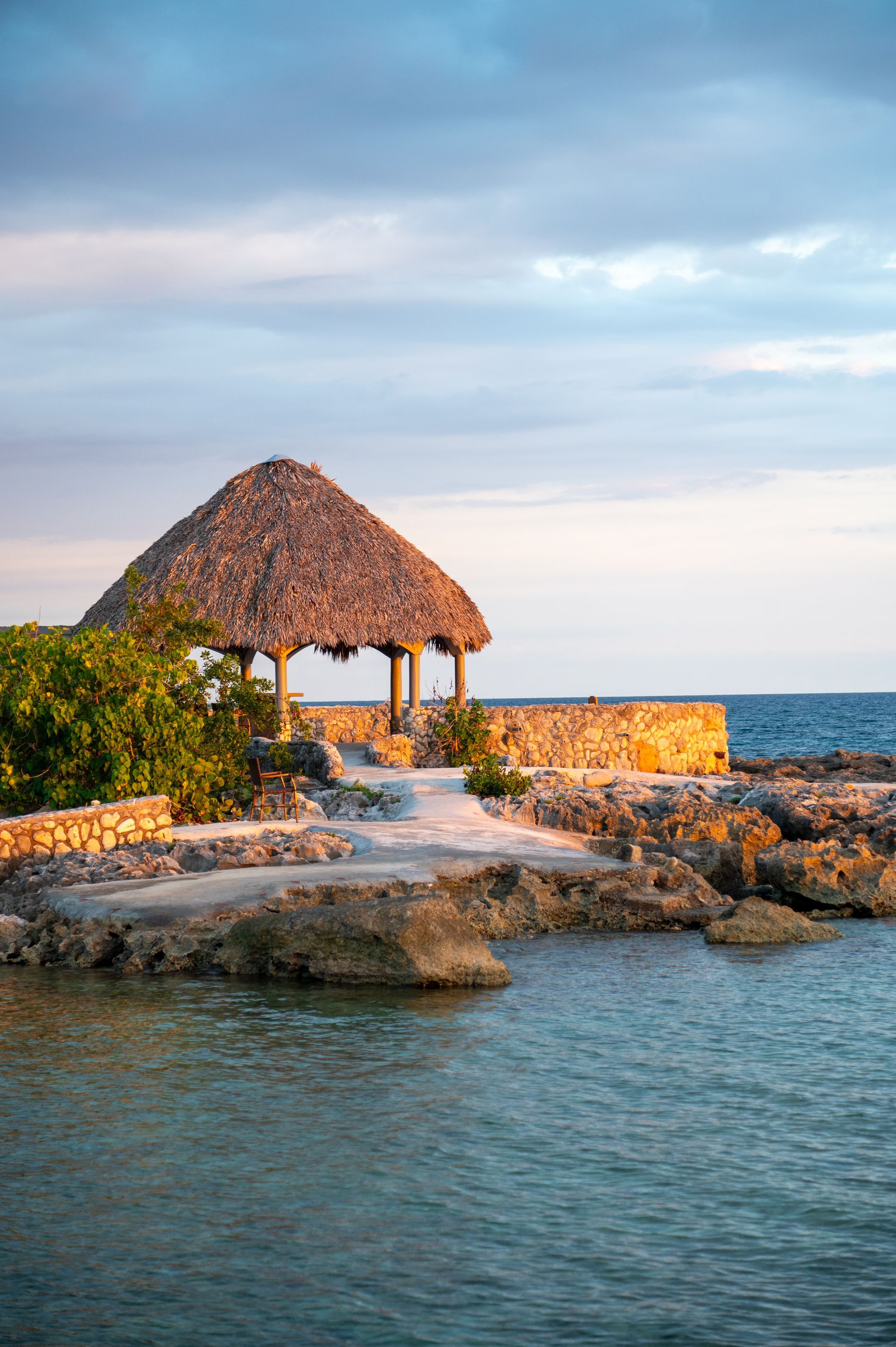 There is a hut on the shore of the ocean.