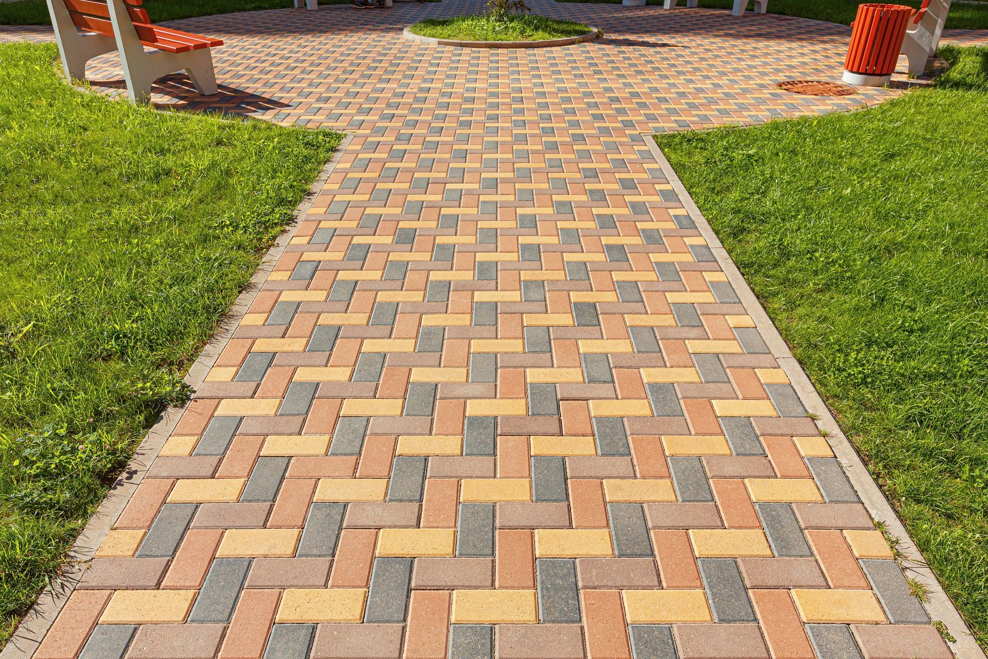 A paved walkway made of interlocking bricks in shades of gray.