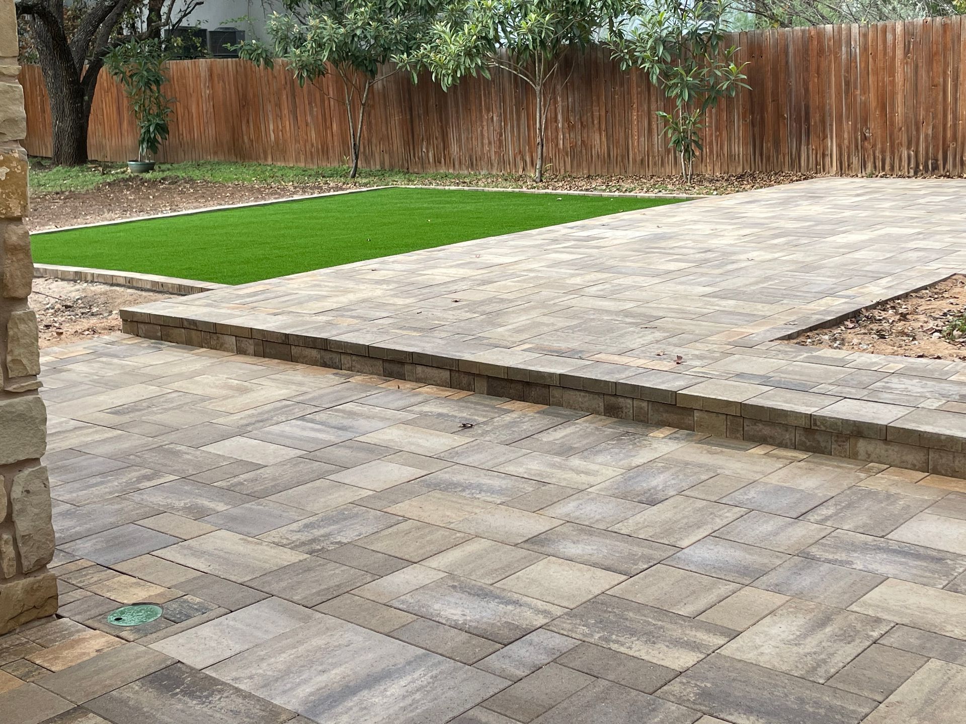 A backyard patio with light-brown paved stones.
