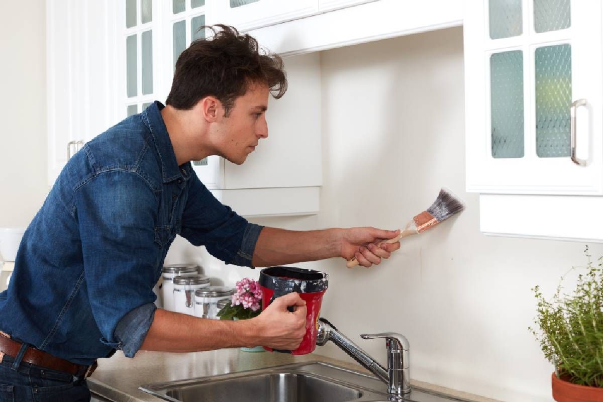 Someone using water-resistant paint for a kitchen sink backsplash near Lexington, Kentucky (KY)