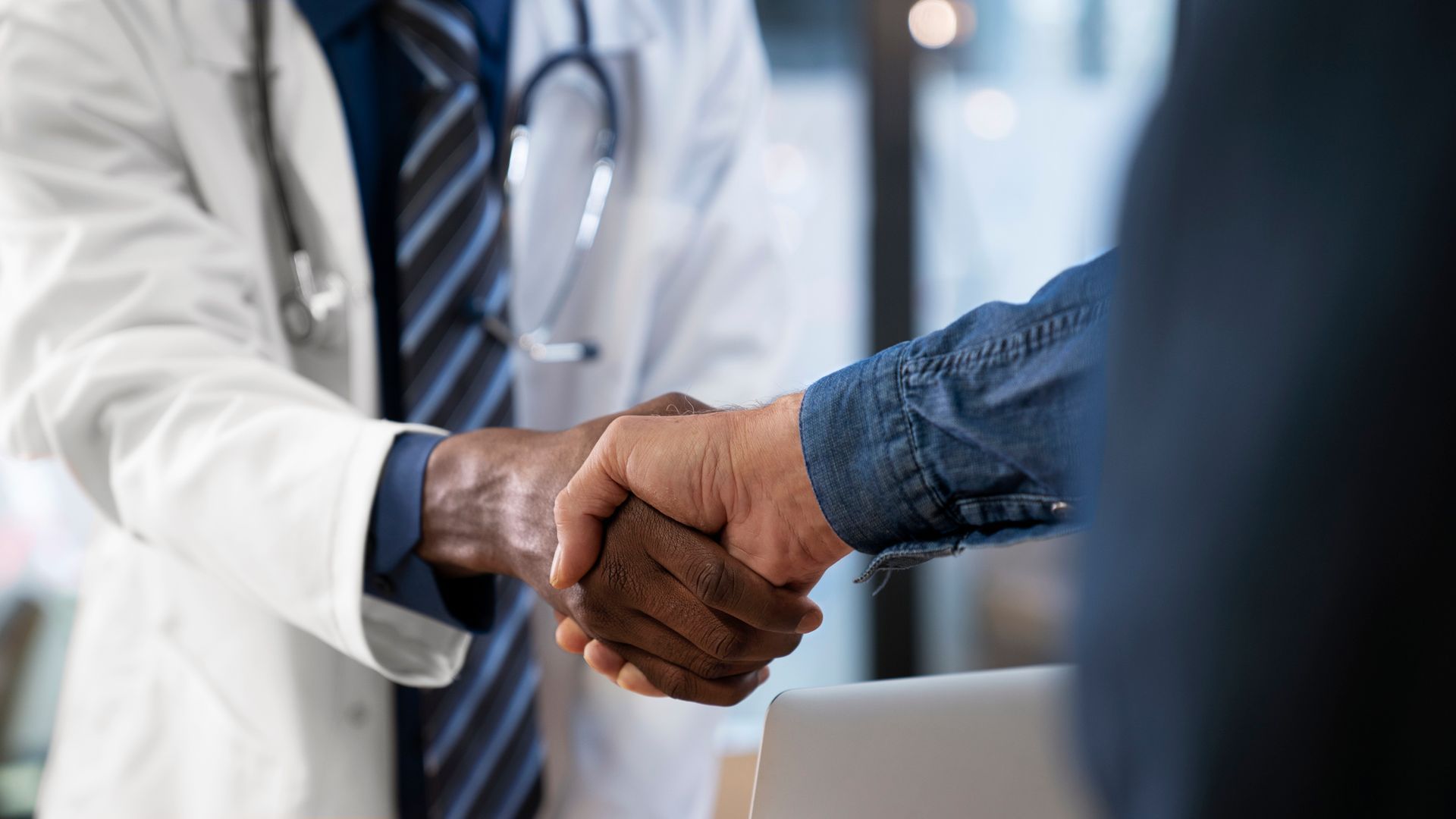 A doctor is shaking hands with a patient in a hospital.
