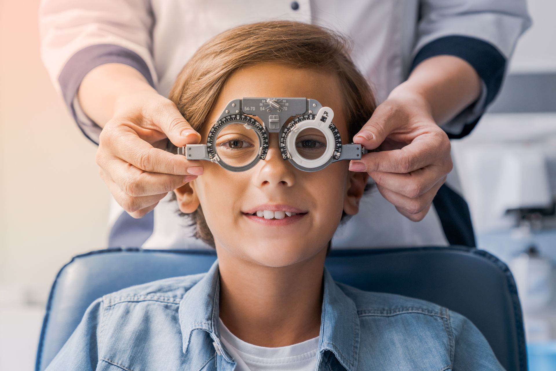 Optometrist adjusting phoropter lenses on smiling patient during an eye exam Optometrist adjusting phoropter lenses on smiling patient during an eye exam