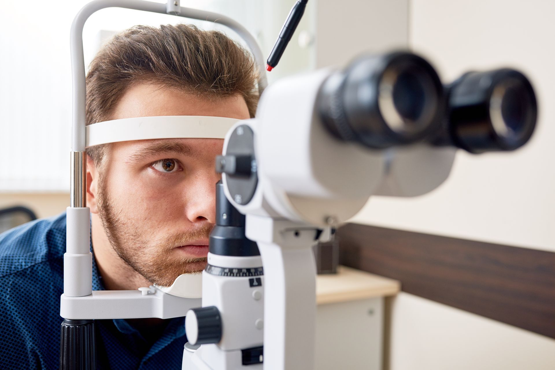 Person using an eye exam machine in an optometrist’s office Person using an eye exam machine in an optometrist’s office
