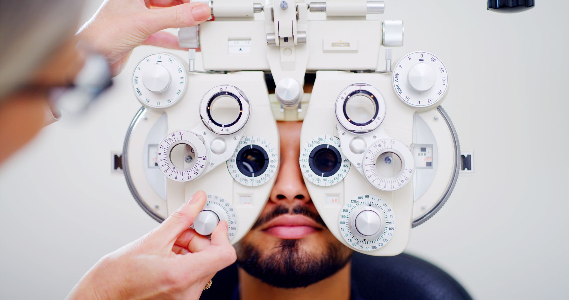 Eye exam with phoropter on a person’s face, technician adjusting the lenses Eye exam with phoropter on a person’s face, technician adjusting the lenses