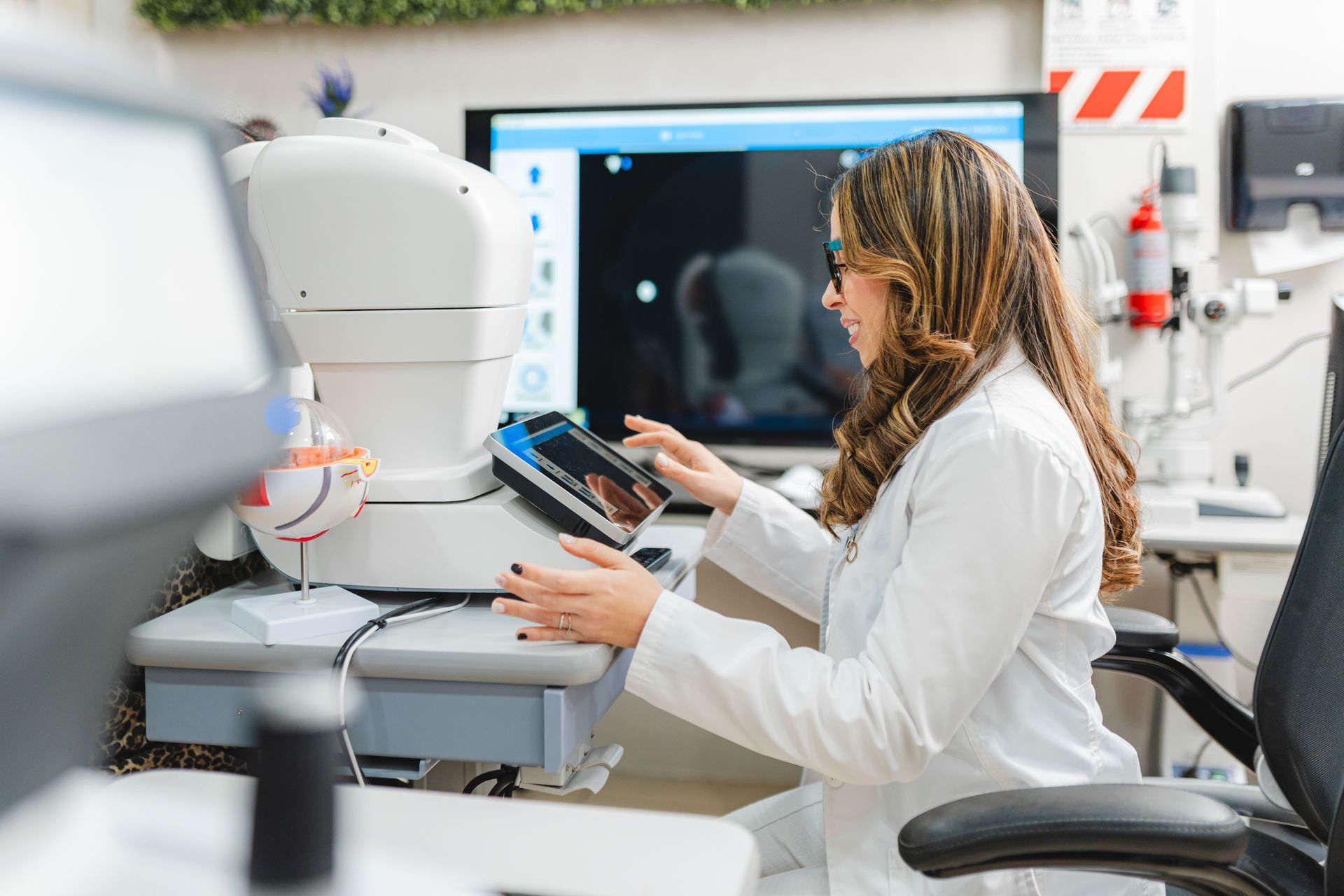 Scientist in a lab coat using a tablet beside a microscope in a bright laboratory