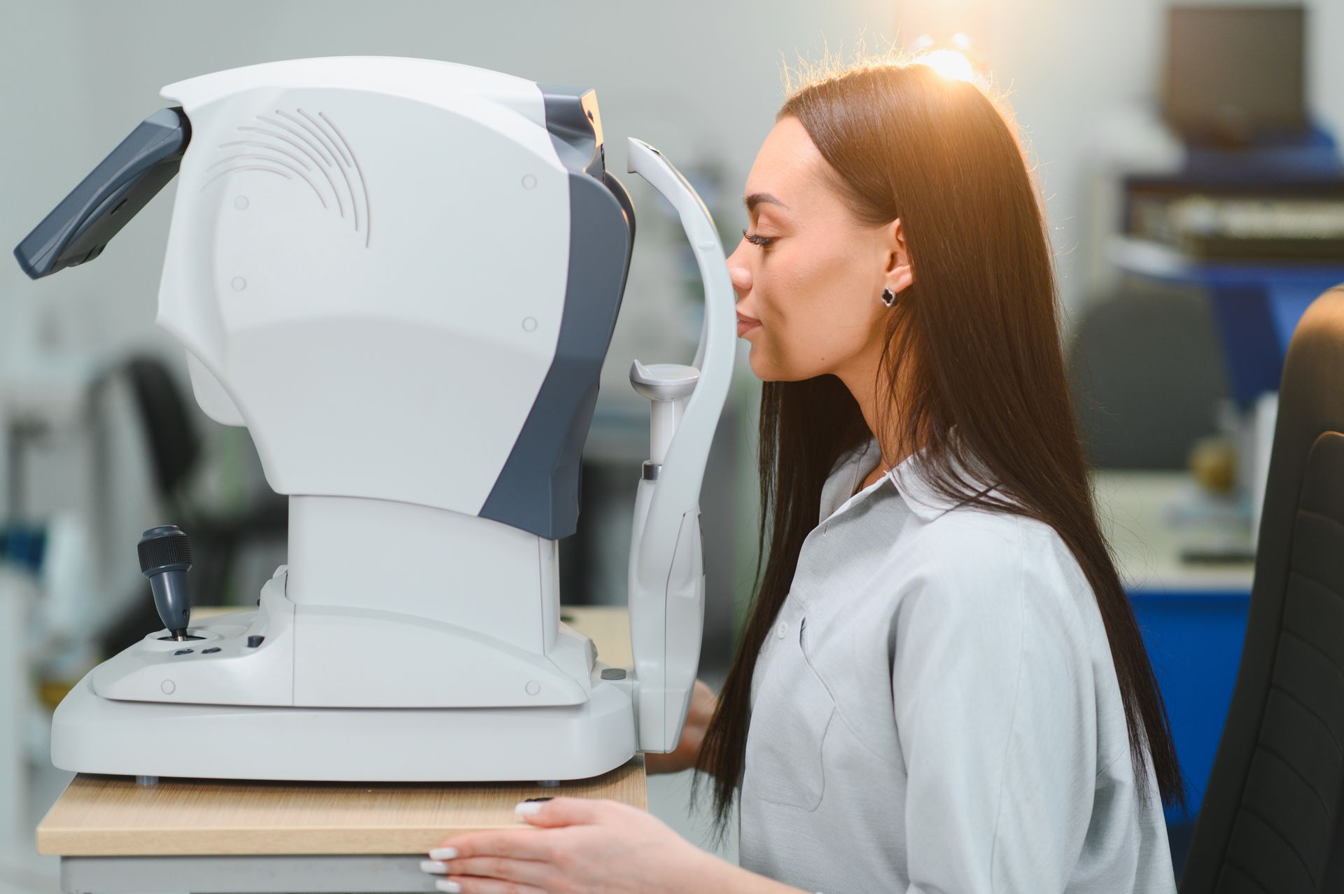 Woman examining a white ophthalmic scanner in a clinical setting Woman examining a white ophthalmic scanner in a clinical setting