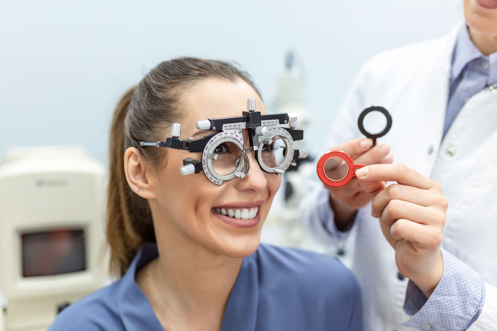 Eye exam with phoropter as optometrist adjusts lenses and smiling patient looks through the device Eye exam with phoropter as optometrist adjusts lenses and smiling patient looks through the device