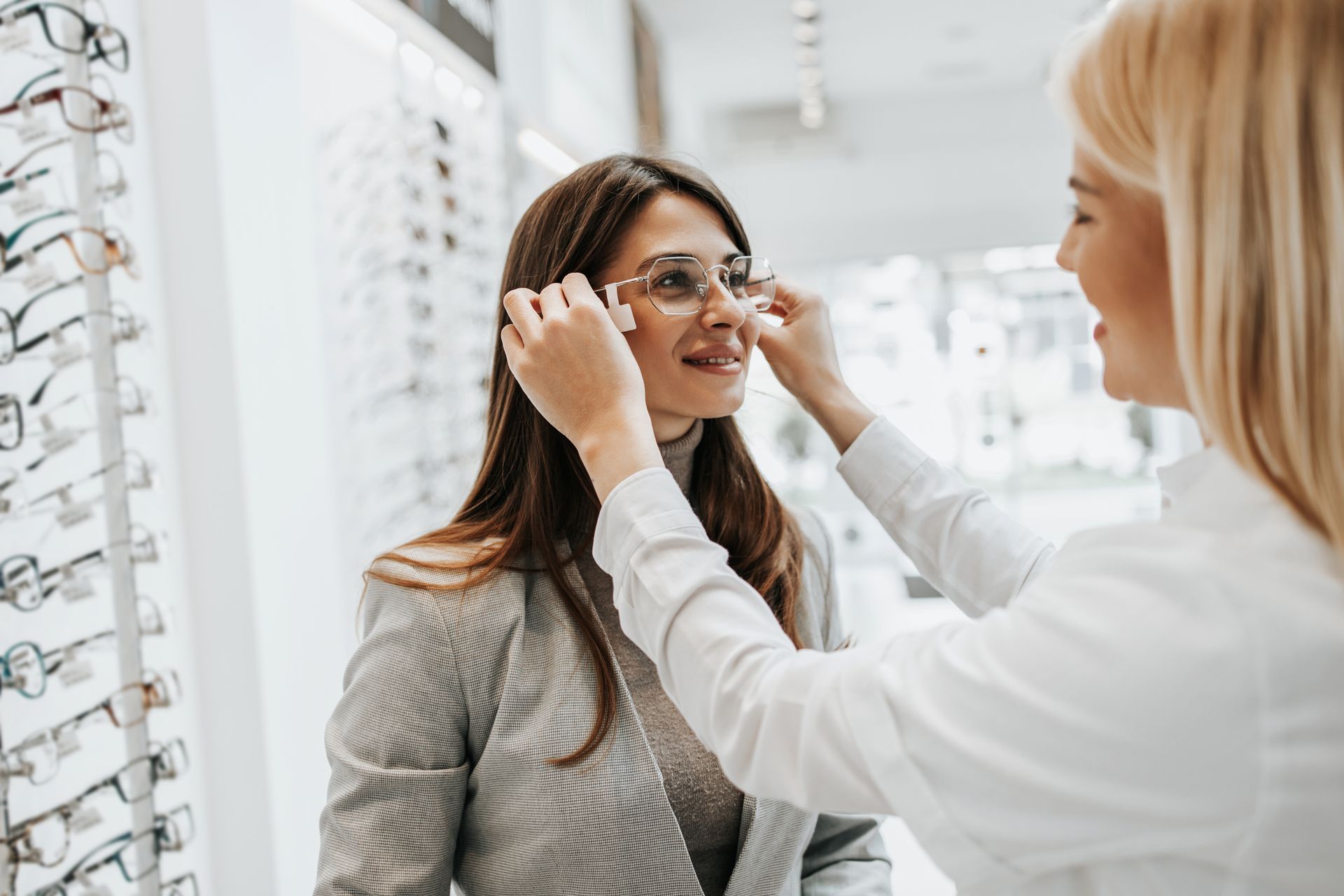 Optician fitting glasses on a customer in an eyewear store