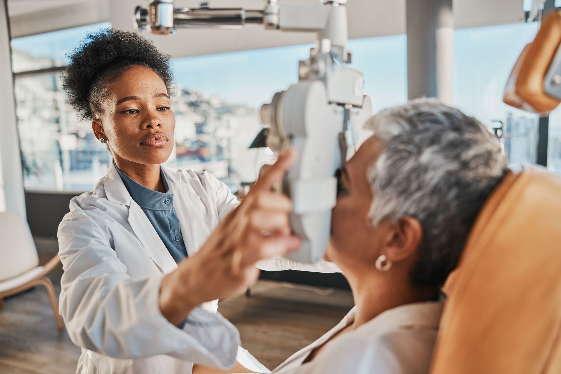 Eye exam in a practice, with a patient reclining while a doctor checks vision with a handheld tool.