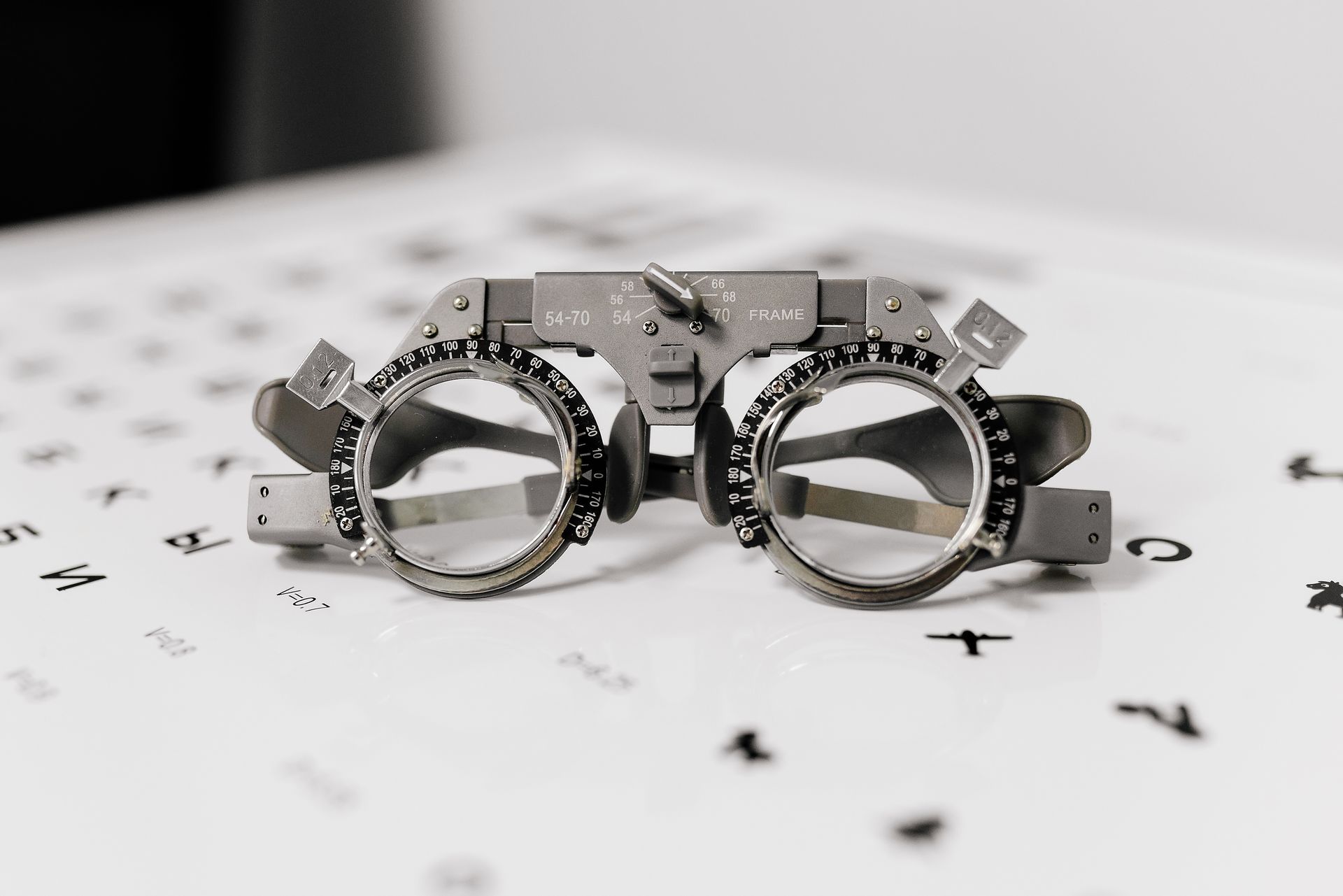 Open metal ring gauge with engraved numbers on a white surface with scattered small screws Open metal ring gauge with engraved numbers on a white surface with scattered small screws