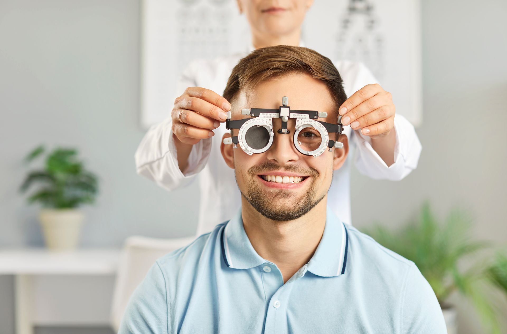Optometrist adjusting trial frames on a smiling man in a bright clinic Optometrist adjusting trial frames on a smiling man in a bright practice