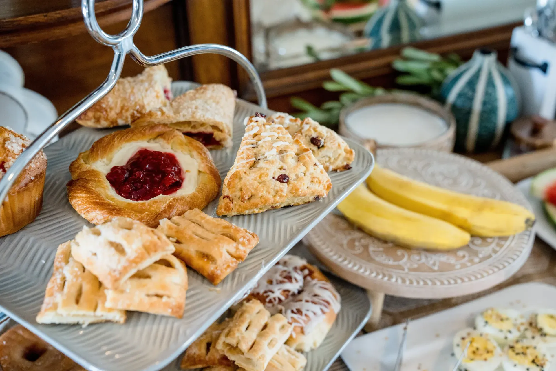 Assorted pastries and bread on tiered serving trays at a buffet table
